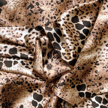 Load image into Gallery viewer, A tan, black and brown African leopard animal print in swirled charmeuse satin.
