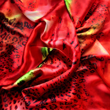 Load image into Gallery viewer, An above view looking down at swirled satin material in an orange, black and green leopard print.