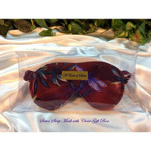 Load image into Gallery viewer, Maroon satin sleep mask with a blue dragonfly. The eye mask is in a clear acrylic gift box. It is placed on top of white satin with various green plants in the background.