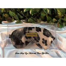 Load image into Gallery viewer, A black and gray leopard animal print satin sleep mask. The sleep mask is in a clear acrylic gift box. There is an A Touch of Satin label on the front of the gift box. It is placed on top of white satin sheets with various green plants in the background.