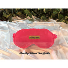 Load image into Gallery viewer, Sain sleep mask in solid pink. The eye mask is in a clear acrylic gift box. It is placed on top of white satin with various green plants in the background.