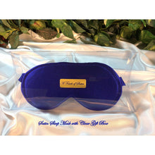 Load image into Gallery viewer, A solid blue satin sleep mask. The sleep mask is in a clear acrylic gift box. There is an A Touch of Satin label on the front of the gift box. It is placed on top of white satin with various green plants in the background.
