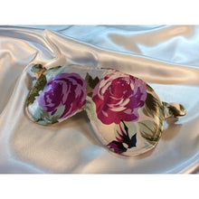 Load image into Gallery viewer, A Green and plum floral print satin eye mask lying on top of white satin sheets. 
