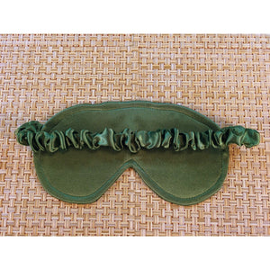 The back side of a sage green eye shade showing the satin covered strap.