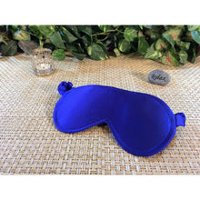 Load image into Gallery viewer, A royal blue satin sleep eye mask with a candle and a stone with the word "relax" behind the sleep mask. Some green floral accent plats are in back.