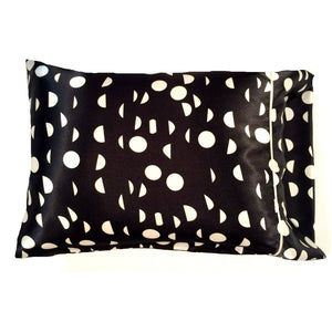 A modern pillow. It has a black cover with white circles and half circles design. The pillow measures 12" x 16".