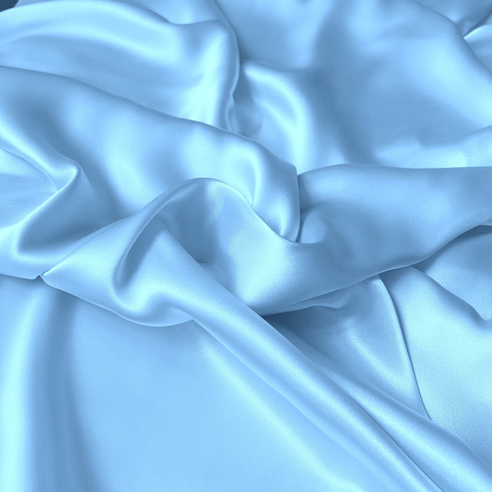a view from above looking down at satin material that is swirled. The color of the fabric is a light blue. A baby blue. 