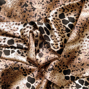 A tan, black and brown African leopard animal print in swirled charmeuse satin.