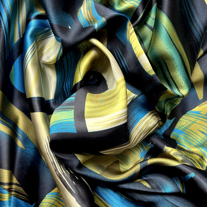 Black, turquoise bue, green and gold abstract print displayed in a swirl.