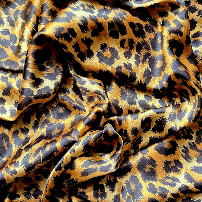 A swirled piece of satin material in a beautiful African leopard animal print in gold and black. 