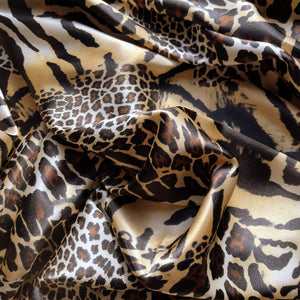 Brown, beige, black and gold cheetah and leopard print satin fabric. Twisted in a swirl to show the pattern.