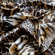 Load image into Gallery viewer, A view from above looking down at a brown, beige, black and gold cheetah and leopard print satin fabric. Twisted in a swirl to show the pattern.
