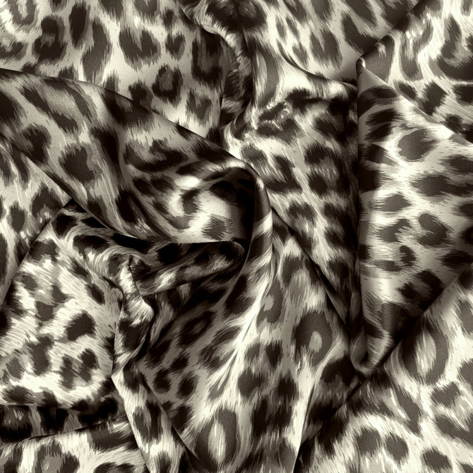 A view from above looking at swirled satin material in a beautiful gray and black leopard print.