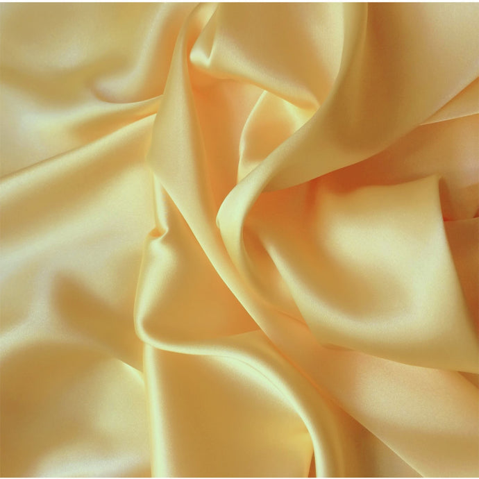 A view from above looking at yellow satin material in a swirled pattern.