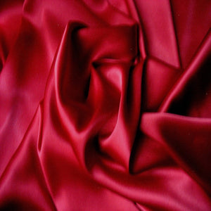 A view of lipstick red satin material swirled.