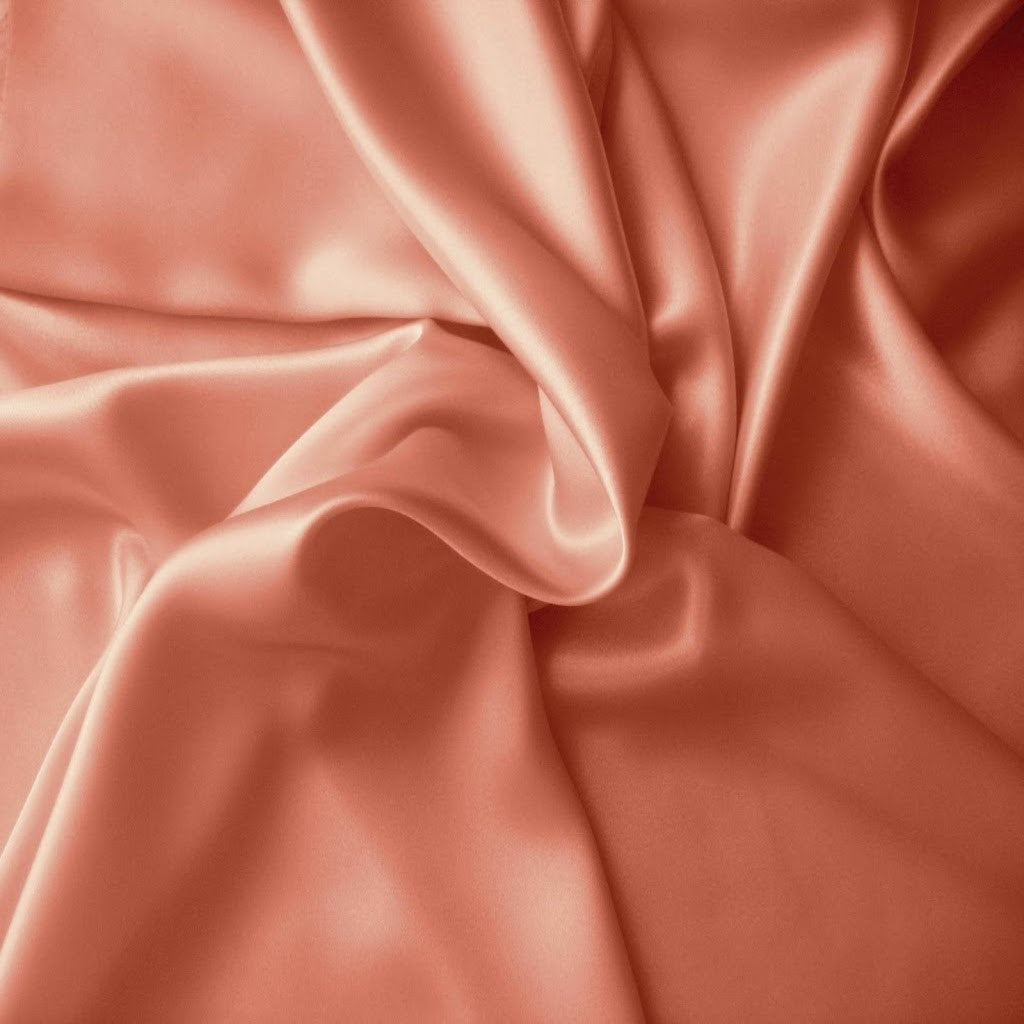 Looking down at a peach colored satin pillowcase in a swirled pattern.