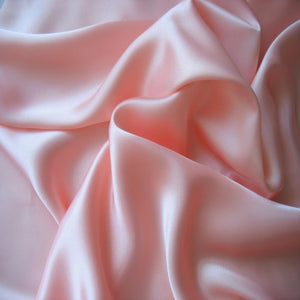 A picture of pastel pink satin material that is swirled.