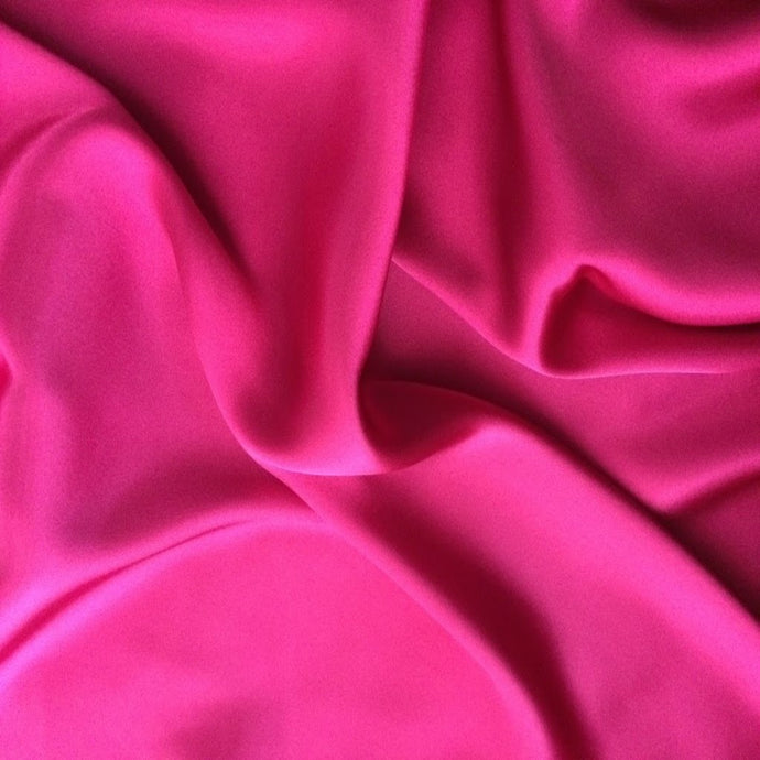 A picture of bubblegum pink satin material that is swirled.
