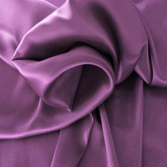 satin material in a solid orchid color. The material is swirled around.