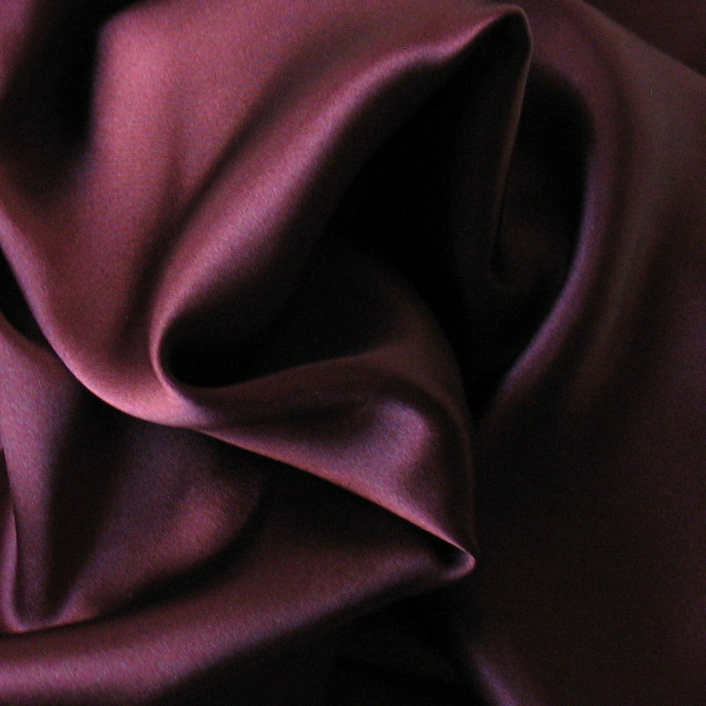 looking at satin material in a solid plum color. The material is swirled.