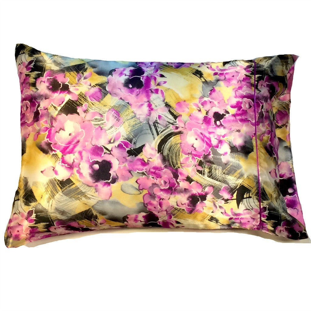 An abstract design satin pillowcase with pink flowers and yellow and black swirls.