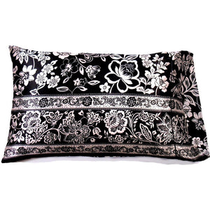 A black satin pillowcase with white flowers and black flowers etched in white. 