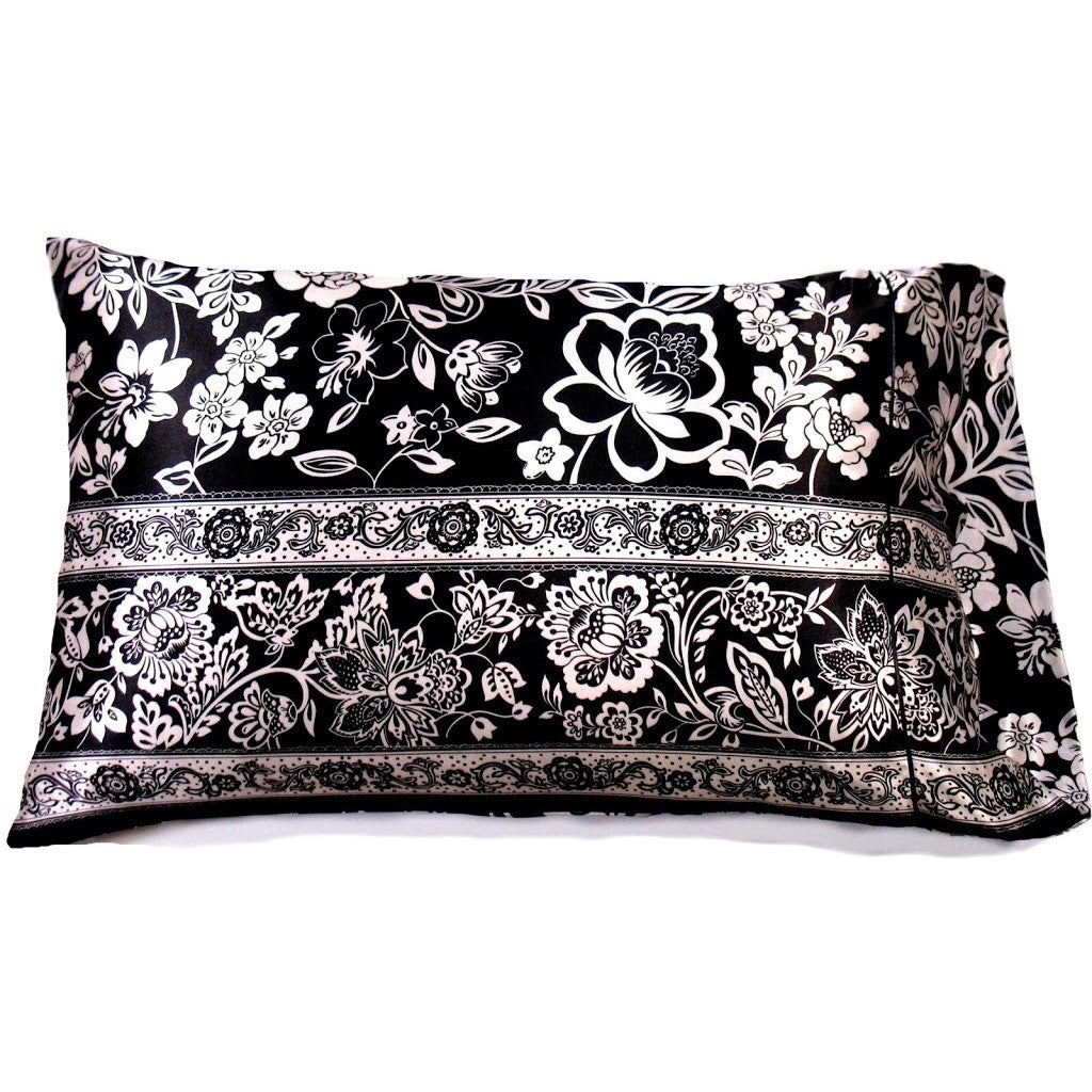A black satin pillowcase with white flowers and black flowers etched in white. 