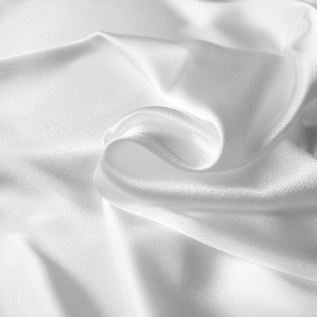 A picture from above of swirled white satin material. 