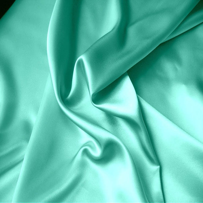 Looking at satin material in a solid color sea foam green. The material is swirled.