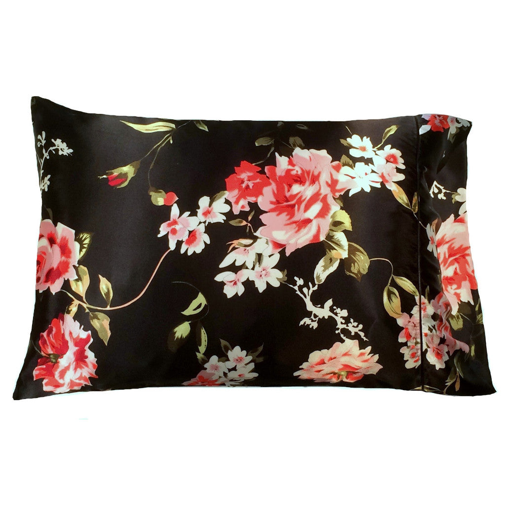 A decorative pillow with a black pillowcase that has white flowers, coral roses print. The pillowcase is on the pillow. The pillow measures 12