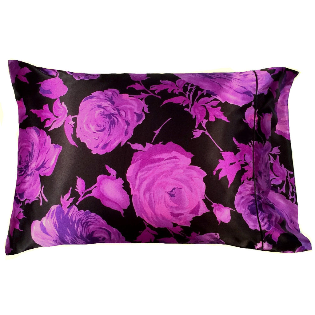 A bedroom pillow with a black satin pillowcase that has purple roses on it. The pillow measures 12