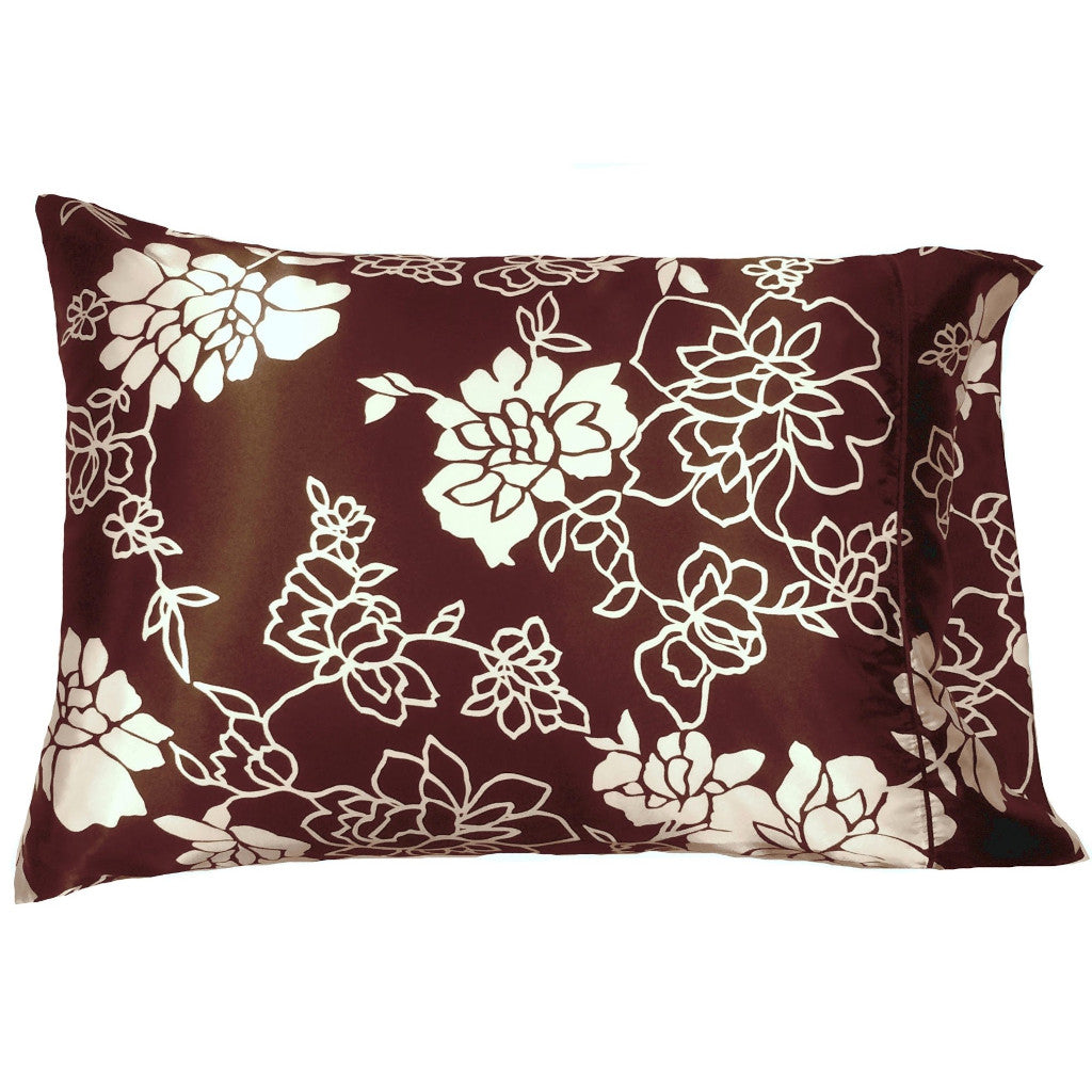 A sofa accent pillow with a brown pillow cover that has white flowers and etched white flowers on it. The pillow measures 12