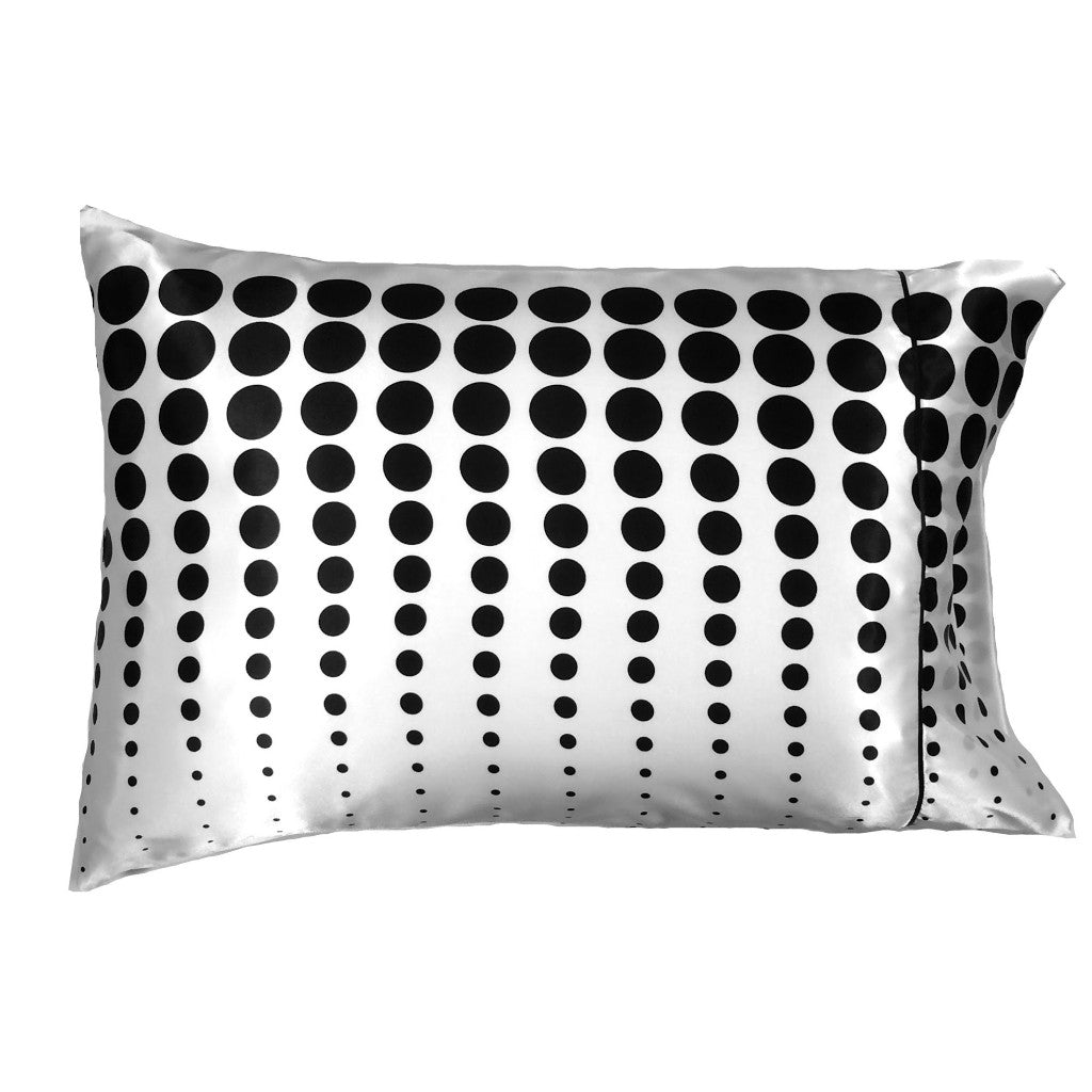 An accent pillow with a white with black polka dots cover. The polka dots go up vertically and the dots go from very small to large. The pillow measures 12