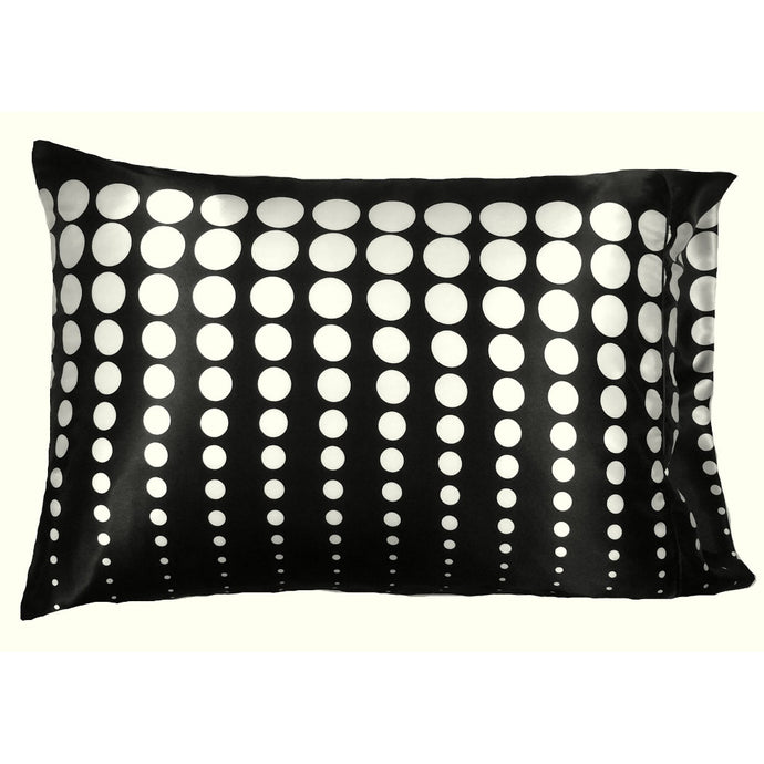 A decorative pillow with a black cover that has white polka dots. The polka dots go vertically and the size of the polka dot goes from small to large. The pillow measures 12
