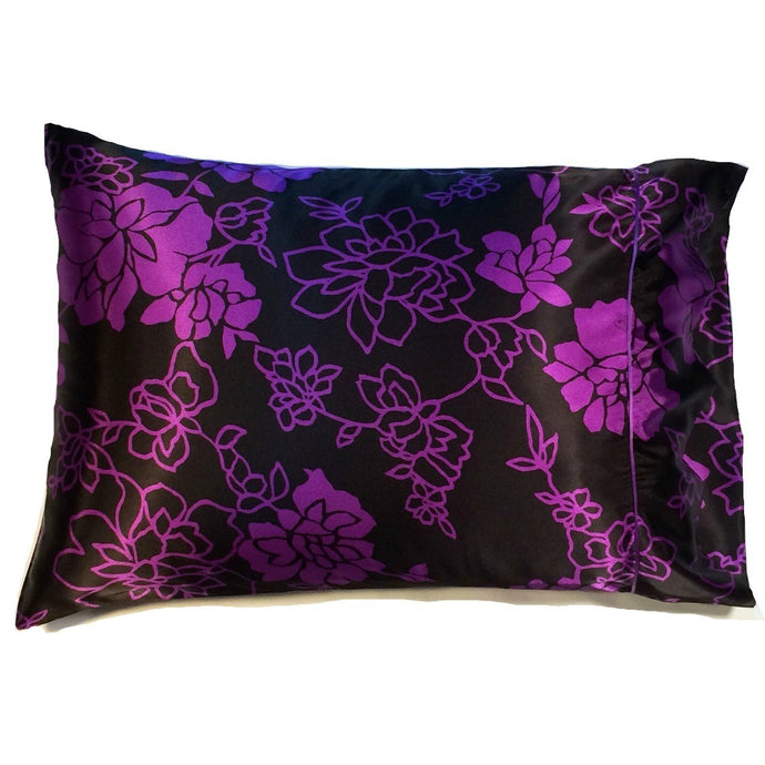 A travel pillow that has a black with purple flowers  satin print pillowcase. The pillow measures 12
