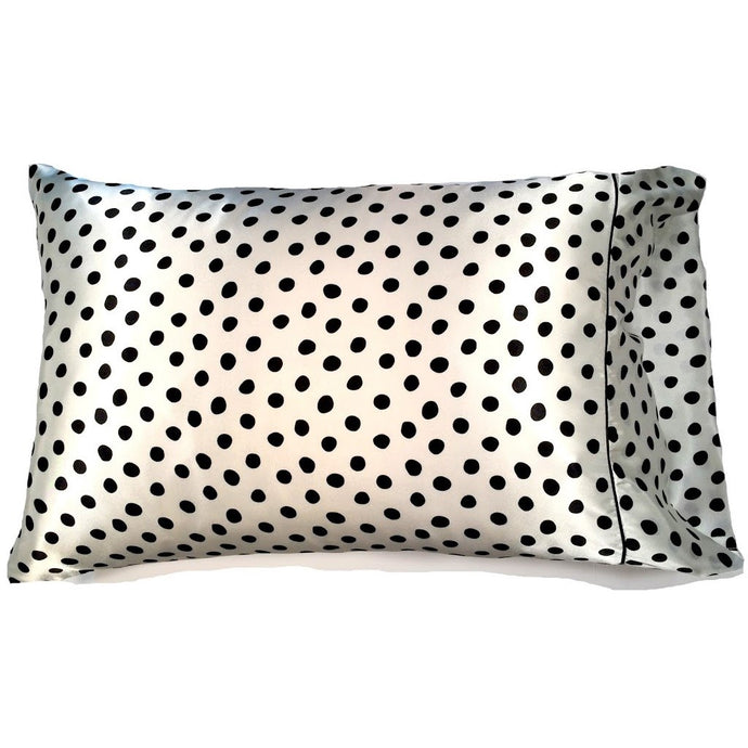 A throw pillow with a white cover that has black polka dots. The pillow measures 12