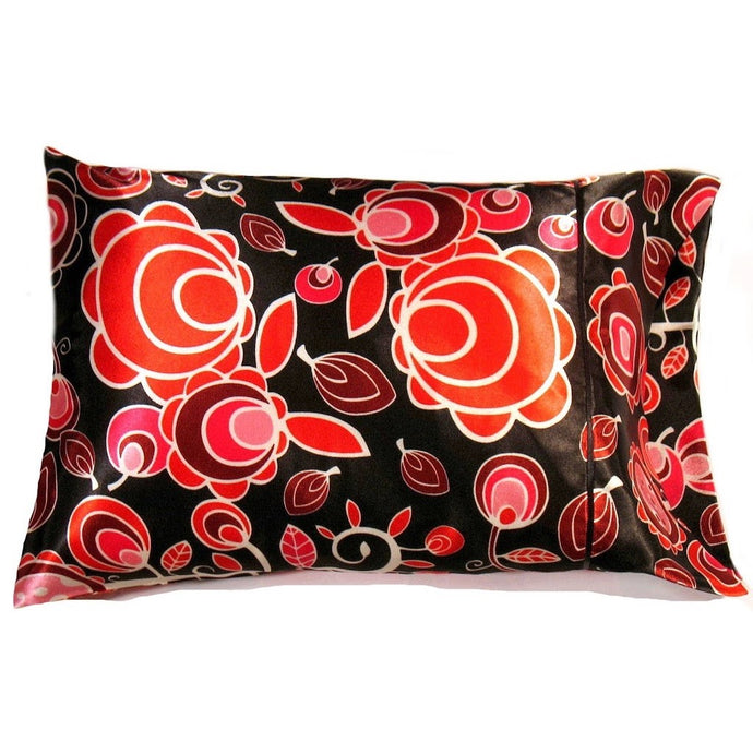 A travel pillow with a black pillowcase that has orange leaves and odd flowers on it. The pillow measures 12