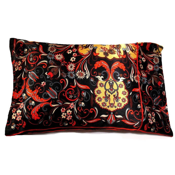 An accent pillow with a black satin cover that has an orange, white and yellow flower print. The pillow measures 12