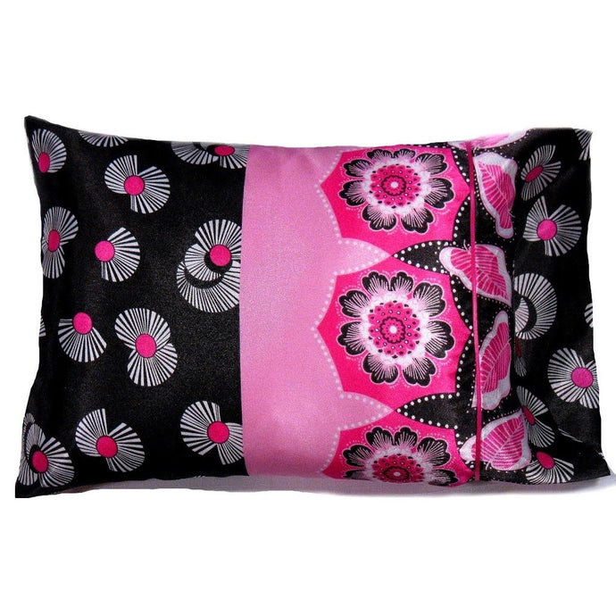 An accent pillow with a back and pink cover. The left side of the pillow is black with white flowers. The right side is in pink with white pink and black flowers. The pillow measures 12