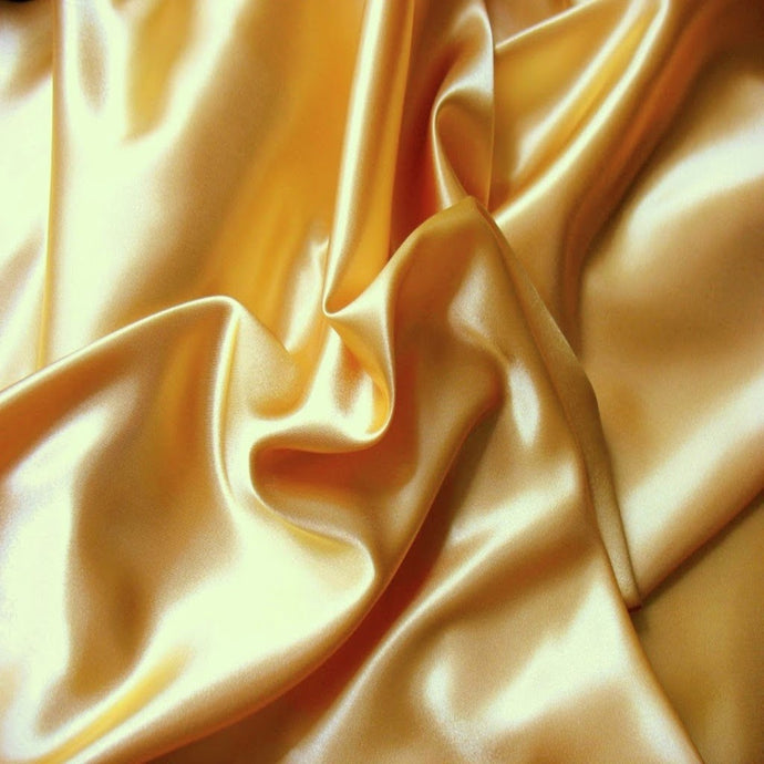 Looking down at light gold satin material in a swirled pattern.