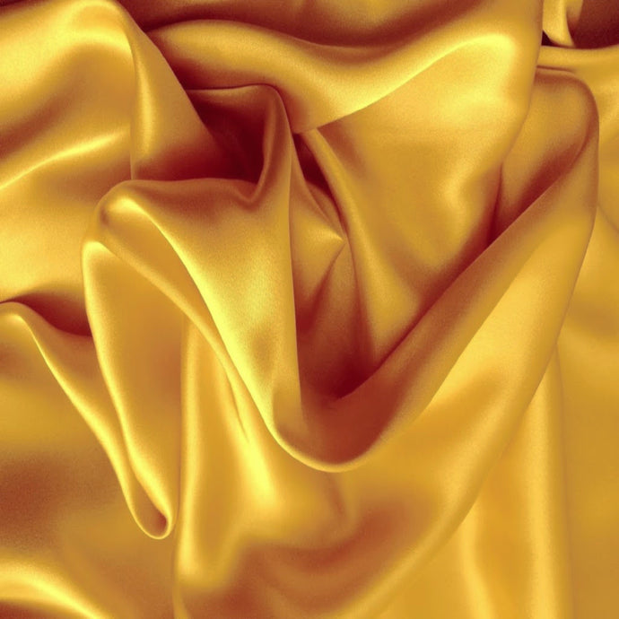 Looking down at gold satin material in a swirled pattern.