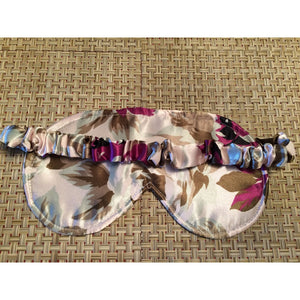The back of a green and plum colored floral print eye mask showing the back with the satin covered strap
