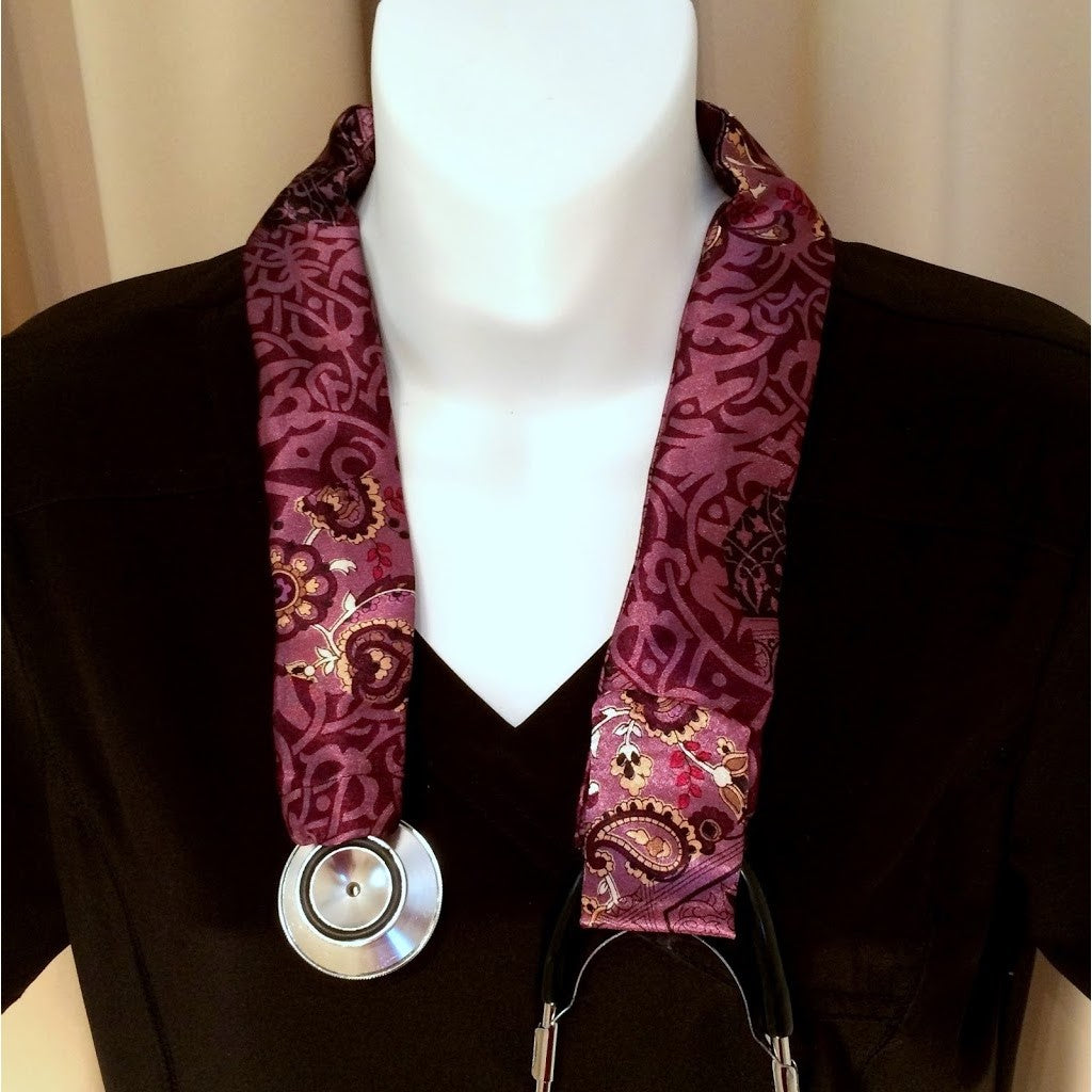 Our physician's stethoscope cover is made from a plum and purple charmeuse satin print. The cover is hanging around the neck of a mannequin.