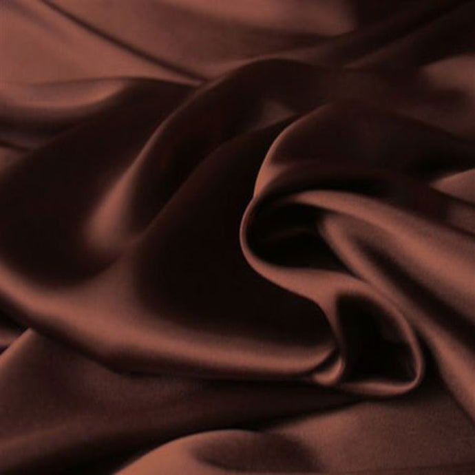 a view from above looking down at brown satin material. The material is in a swirl pattern.