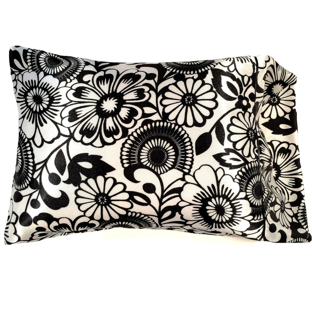 A travel pillow with a white cover that has black flowers on it. The pillow measures 12