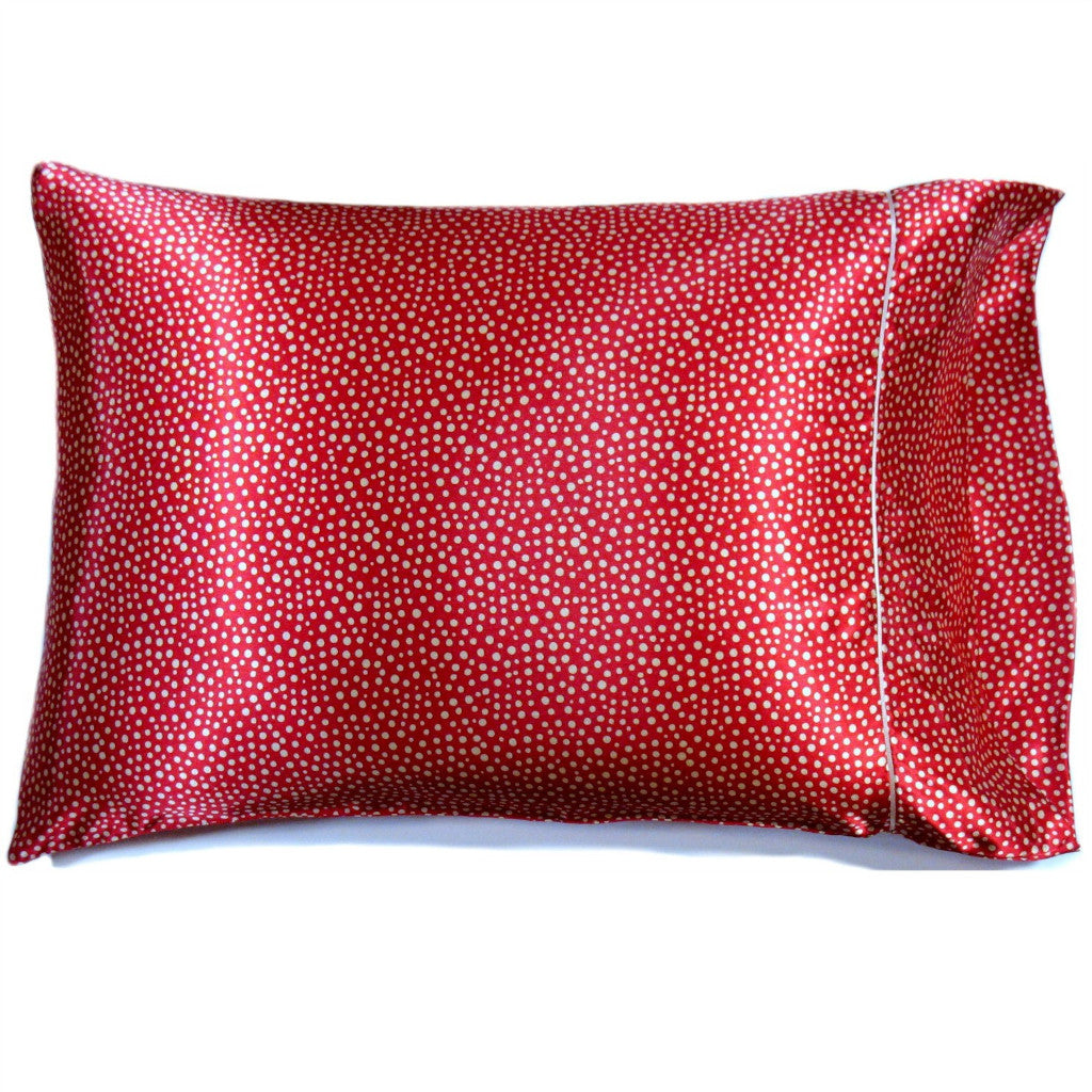 A bed pillow with a rust color and small white polka dots satin cover. The pillow measures 12