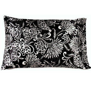 A couch throw pillow with a black satin cover with white flowers on it. The pillow measures 12" x 16".