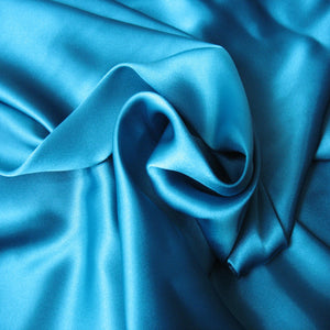 satin material in a solid turquoise color. The material is swirled.