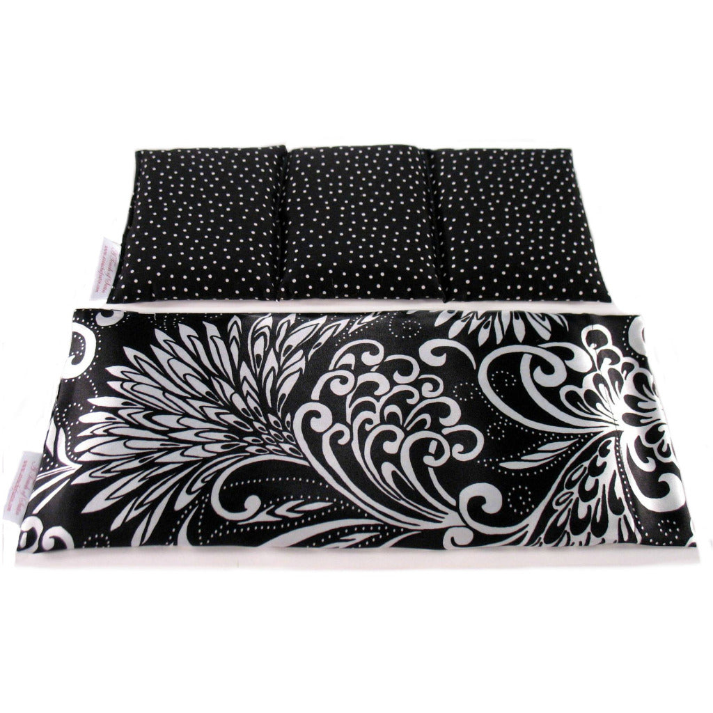Black therapy wrap with white flowers. Behind the wrap is an insert sewn in three sections in a black with white polka dots cotton print.