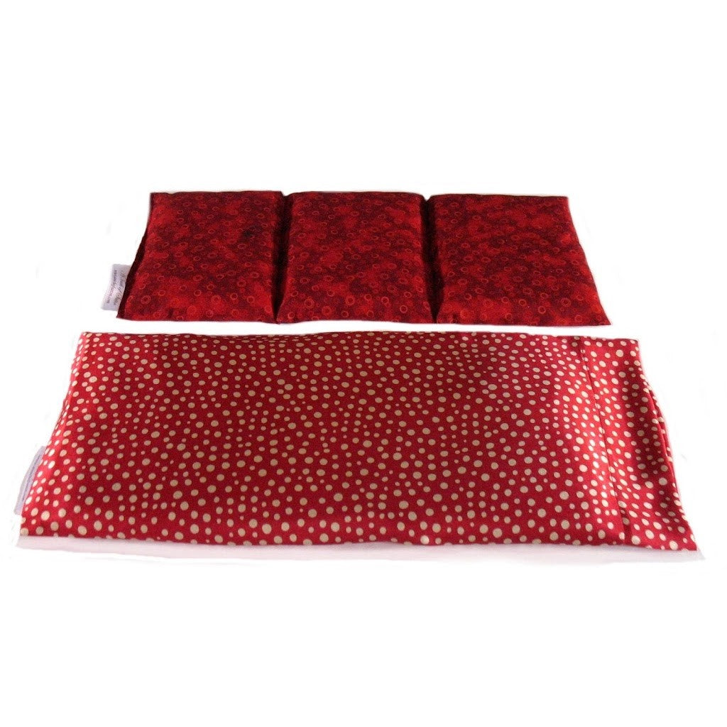 A therapy pad with an orange satin cover with beige various sized polka dots. Behind the therapy pad is a cotton insert. The insert is sewn into three sections. The insert cover is in a rust color.